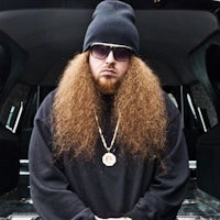 a man with long hair standing in the back of a car